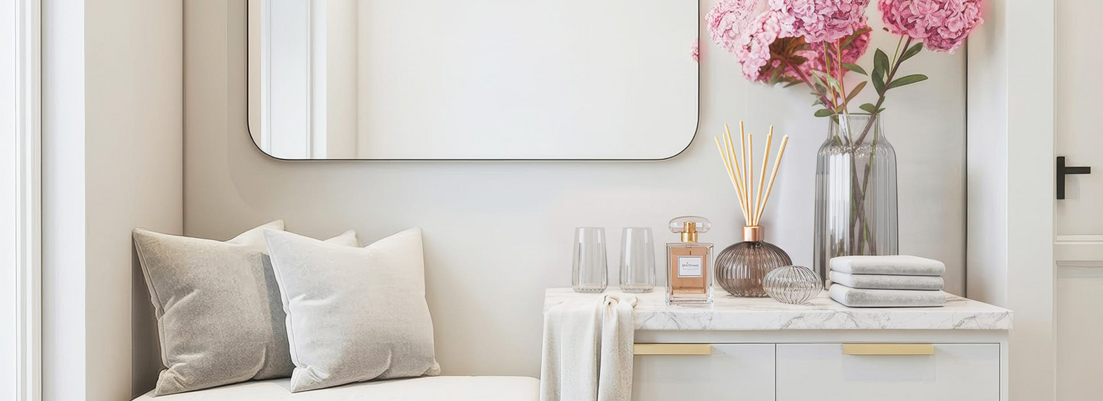 Modern room with decorative pillows, a wall mirror, flowers, and scented diffusers on display.